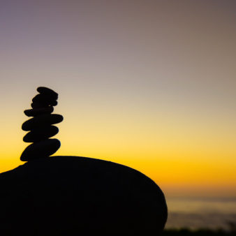 Silhouette stack of small rocks on a large rock